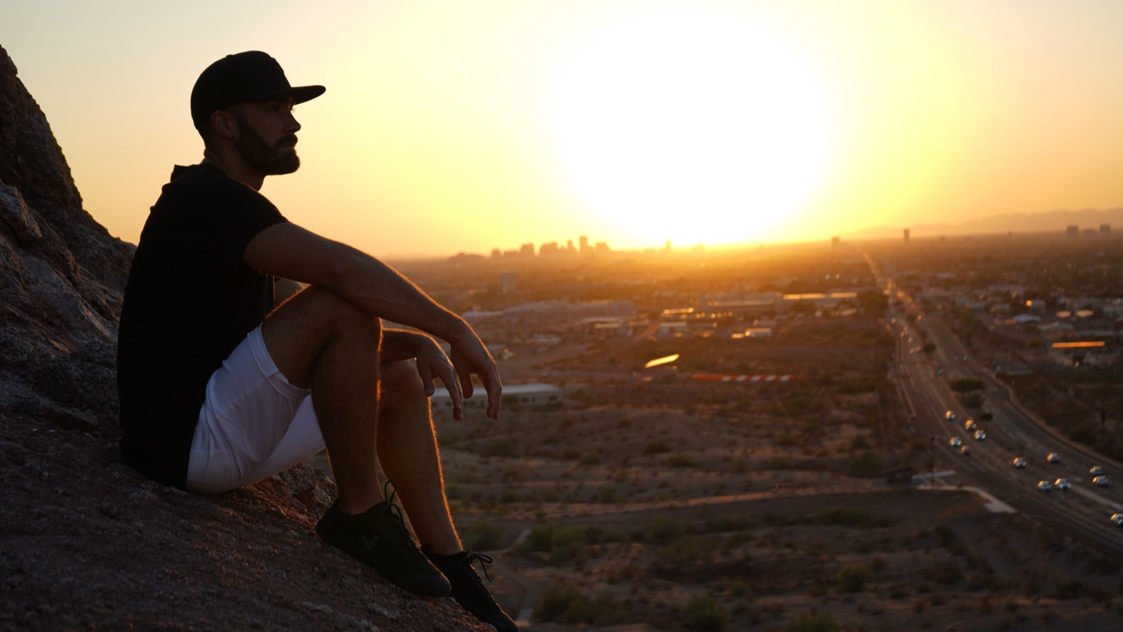 Ryan McBurney silhouetted on a Papago Park butte at sunset, overlooking Phoenix